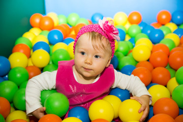 Fototapeta na wymiar Happy child girl in colored ball on playground.
