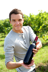 Young winegrower presenting wine bottles