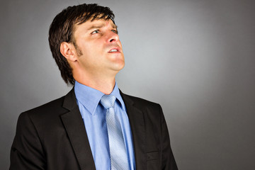 Closeup portrait of an angry young businessman looking up