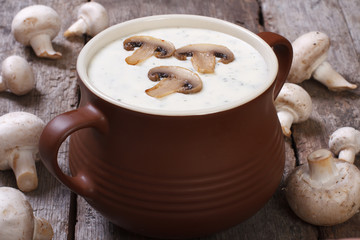 Puree soup with mushrooms in a pot on the old wooden table
