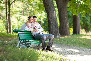 Fototapeta premium Bride and groom in bright clothes on the bench