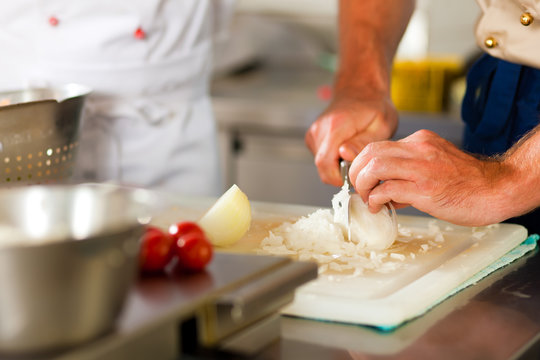 Chef preparing onion in restaurant or hotel kitchen