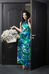 Young woman with a basket in hand enters the door