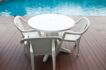 chairs and tables next to a swimming pool