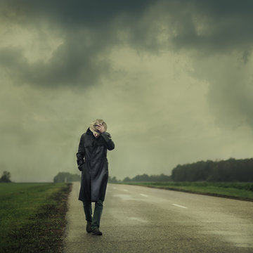 Grim Man In A Black Cloak Walking On The Road Alone