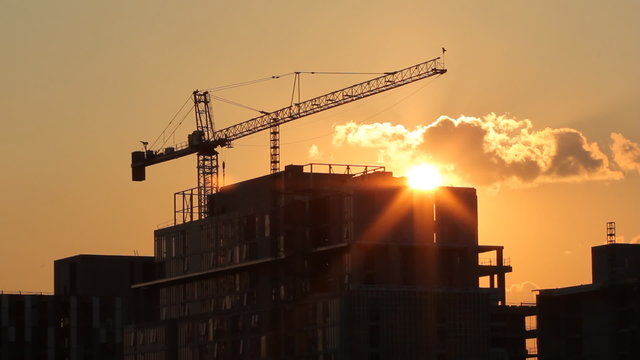 Tower crane and condominium at sunset. Real time shot.