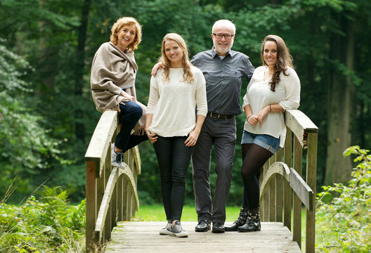 Mother father and daughters standing on bridge in the forest