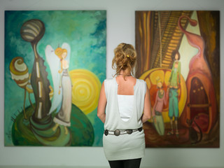 woman contemplating colorful paintings