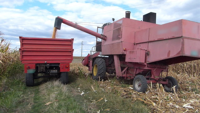 Combine loading harvested corn into tractor-trailer