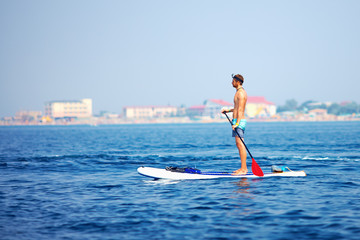 young man standing on paddle board in the sea