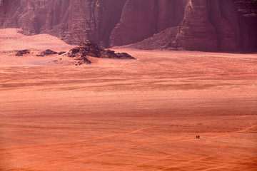 Fototapeta na wymiar Bedouins riding on camels in the dessert of Wadi Rum in Jordan