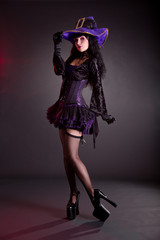 Pretty witch in purple and black gothic Halloween costume
