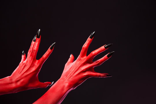 Spooky red devil hands with black nails, real body-art