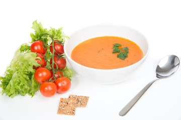 Tomato cream soup garnished with salad leaves crispbread and spo