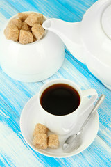 Cup of coffee, teapot and sugar-bowl on color wooden background