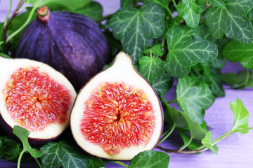 Ripe figs in leaves on wooden table close-up
