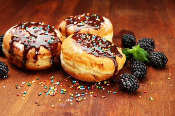 Tasty donuts with chocolate and berries on wooden table