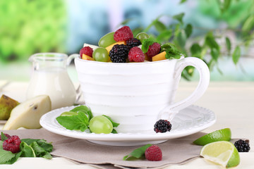 Fruit salad in cup on wooden table on nature background