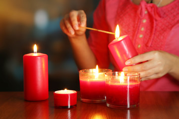 Woman lights candles on bright background