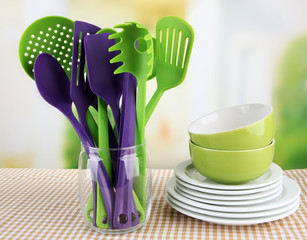 Plastic kitchen utensils in stand with clean dishes