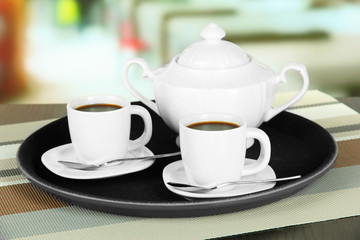Cups of coffee on tray on table in cafe