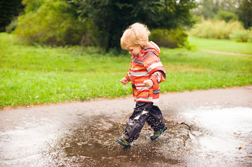 Fototapeta premium Boy running and jumping in puddles