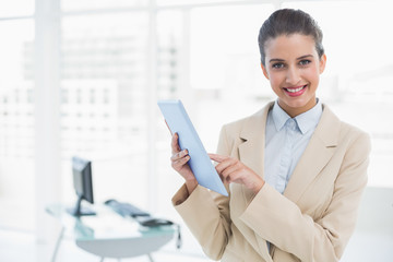 Cheerful smart brown haired businesswoman using a tablet pc