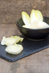 Fresh chicory witloof heads in rustic setting with wooden backgr