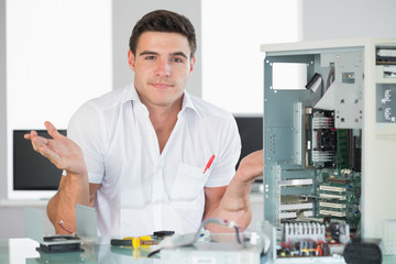 Confused computer engineer sitting behind open computer