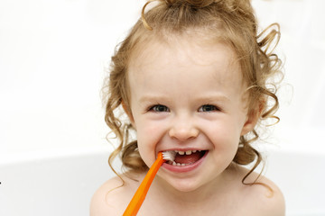 Little toddler brushing teeth in the bath