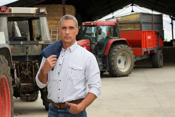 Naklejka premium Farmer stood in front of tractors
