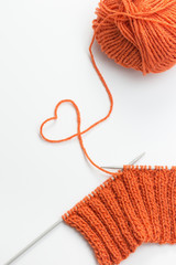 Incomplete knitting project with ball of orange wool