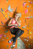 smiling girl is engaged in rock climbing on climbing gym