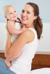 Happy mother holding and playing with cute smiling baby