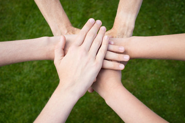 Arms uniting above grass background