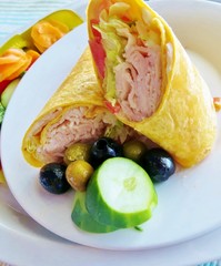 A turkey wrap with cucumbers and olives and a side salad