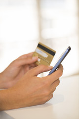 Close-up woman's hands holding a credit card and using cell phon