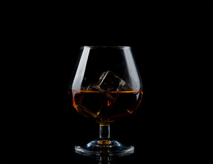 Glass of whiskey with ice on black