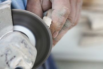 construction worker using an angle grinder cutting tile