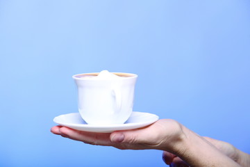 Female hand holding cup of hot latte coffee cappuccino