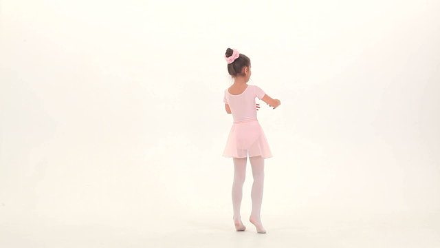 Little ballet dancer performing ballet pas in a studio
