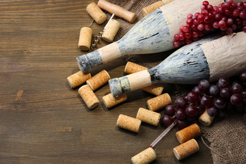 Old bottles of wine, grapes and corks on wooden background