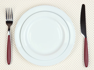 Knife, color plate and fork, on color background