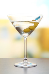 Martini with green olives on table in bar