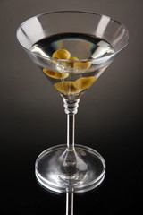Martini with green olives on grey background