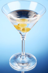Martini with green olives on blue background
