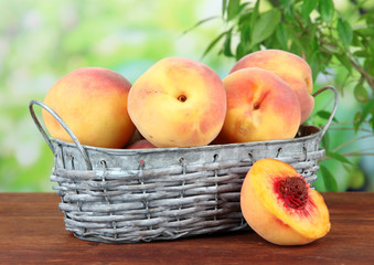 Ripe sweet peaches in wicker basket, on bright background
