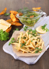 French fries on tracing paper on board on wooden table