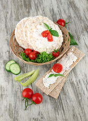 Tasty crispbreads with vegetables on wooden background