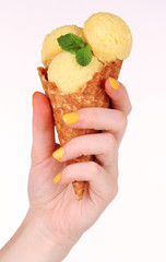 Hand holding yellow ice cream with mint in  waffle cone